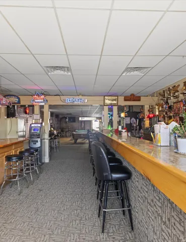 Expansive bar area featuring a granite-style countertop, wood bar rail, and patterned carpet flooring