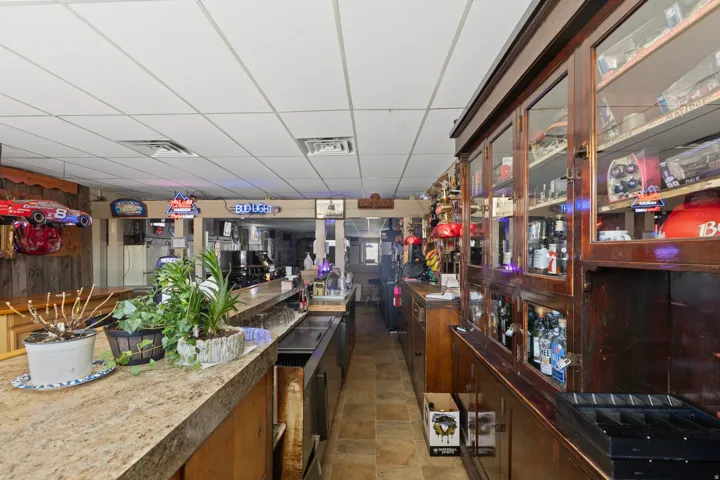 Full-length service bar with a stone-finish countertop, wood-paneled walls, and extensive built-in wooden display cabinetry