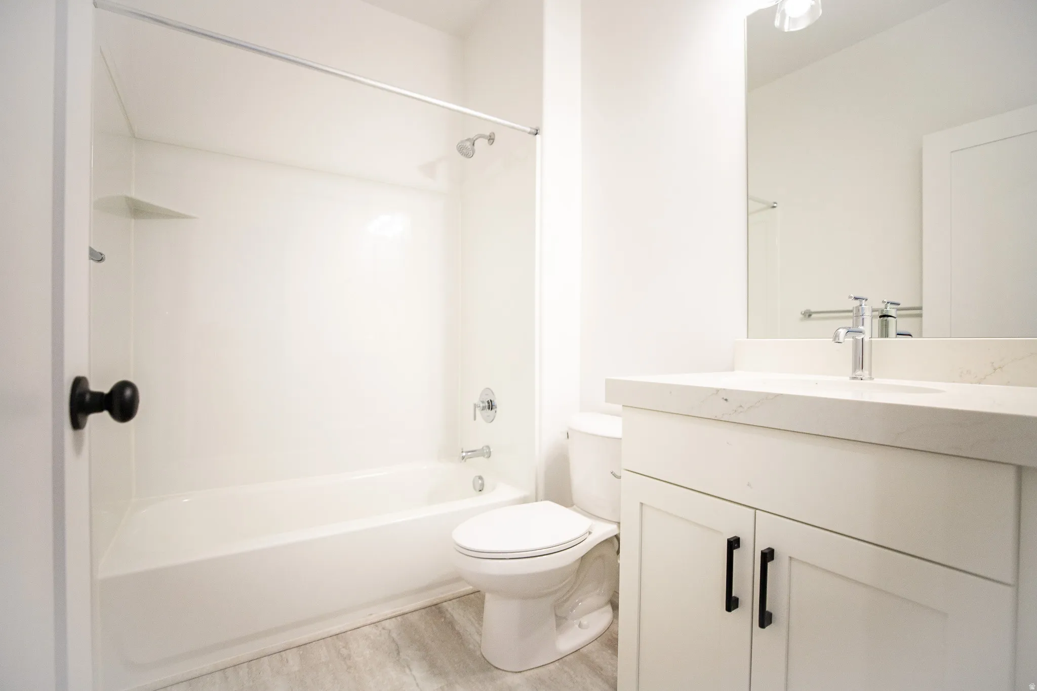 Third full bathroom in full-finished basement with painted white wood cabinets and quartz slab countertops.