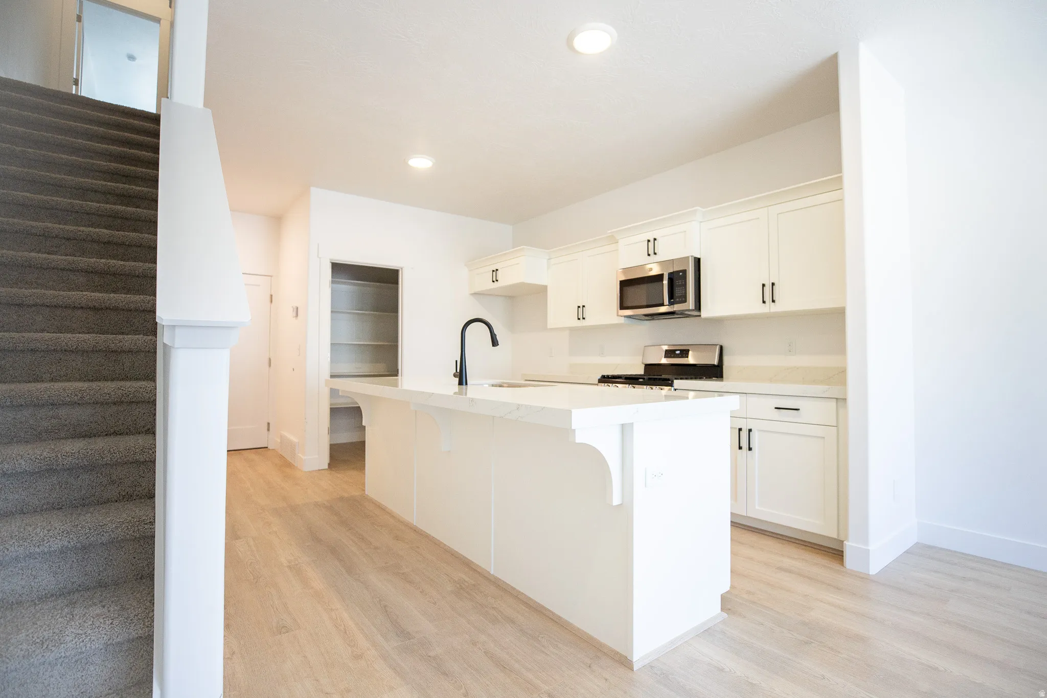 Terrific kitchen with painted white wood cabinets, walk-in pantry, quartz slab countertops, gas range, microwave and disposal.