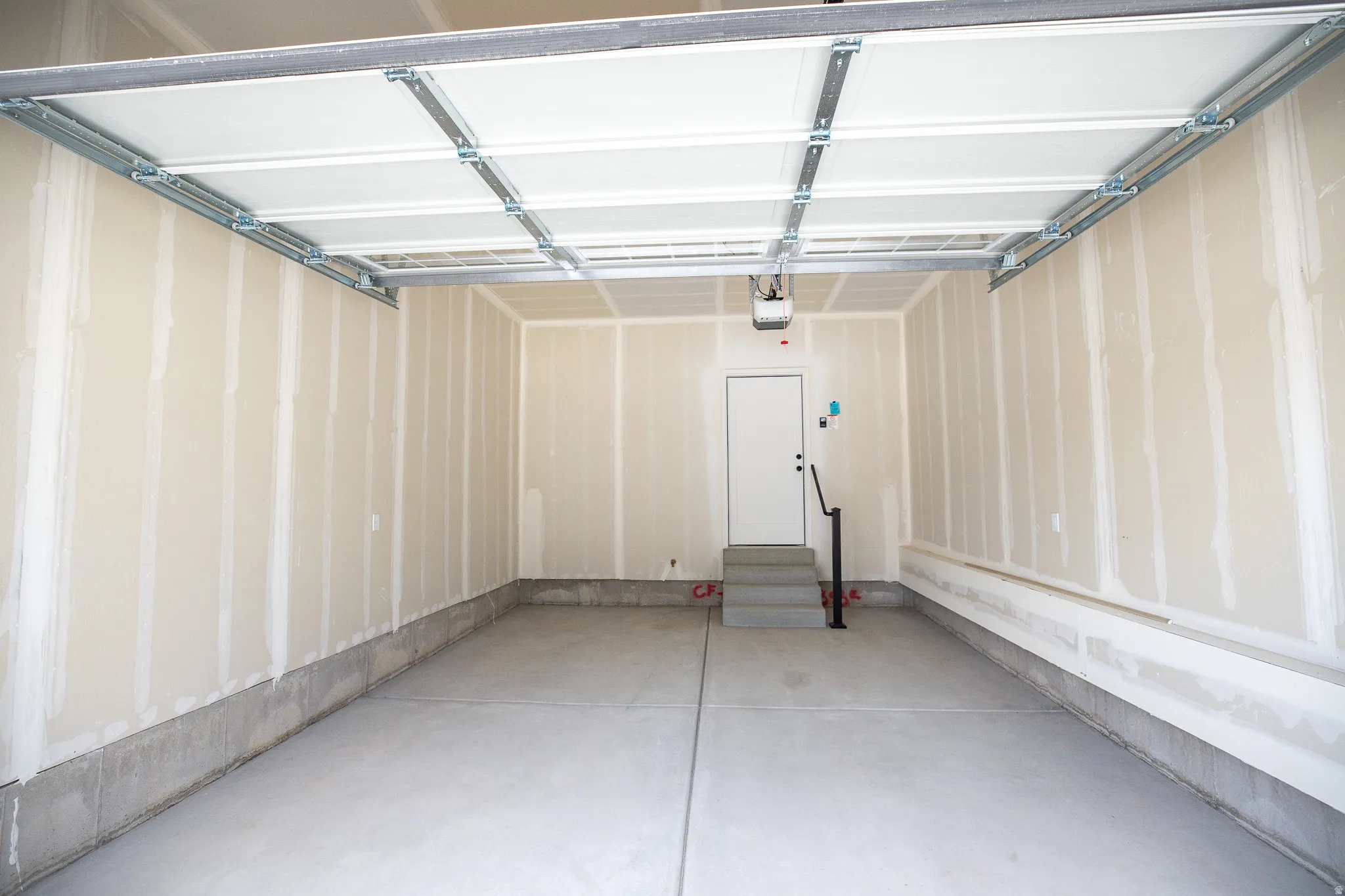 Single car garage with additional space for storage and taped finish.