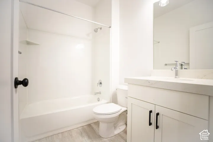 Third full bathroom in fully-finished basement with painted white wood cabinets and quartz slab countertops.