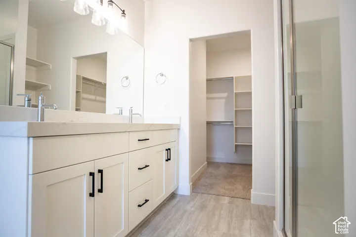 Primary bath with dual sinks, painted white wood cabinets, quartz slab countertops and spacious walk-in shower.