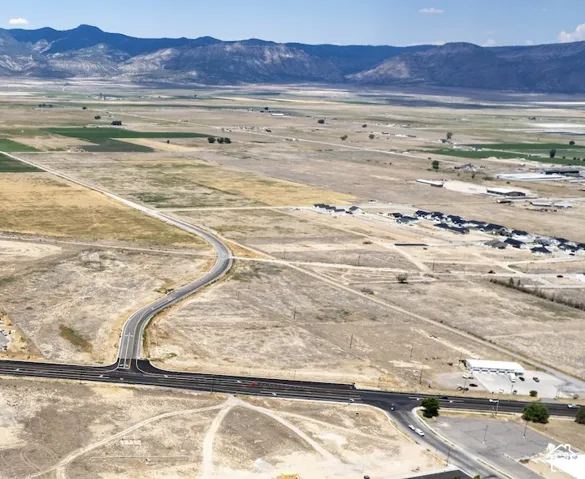 Expansive undeveloped land featuring paved roadways, surrounding residential development, and a mountainous backdrop