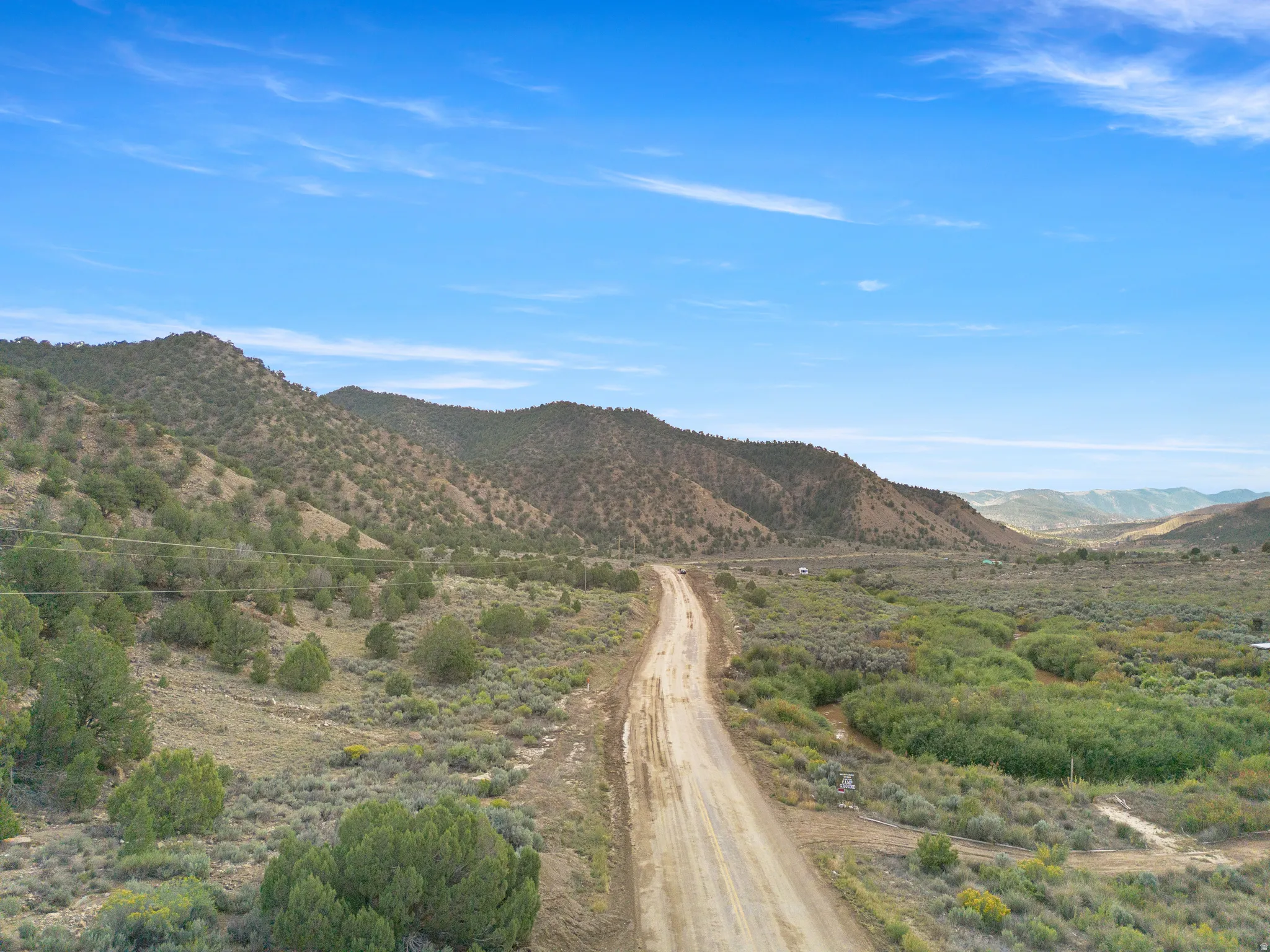 Expansive rural landscape featuring a dirt road, varied terrain, and distant mountains