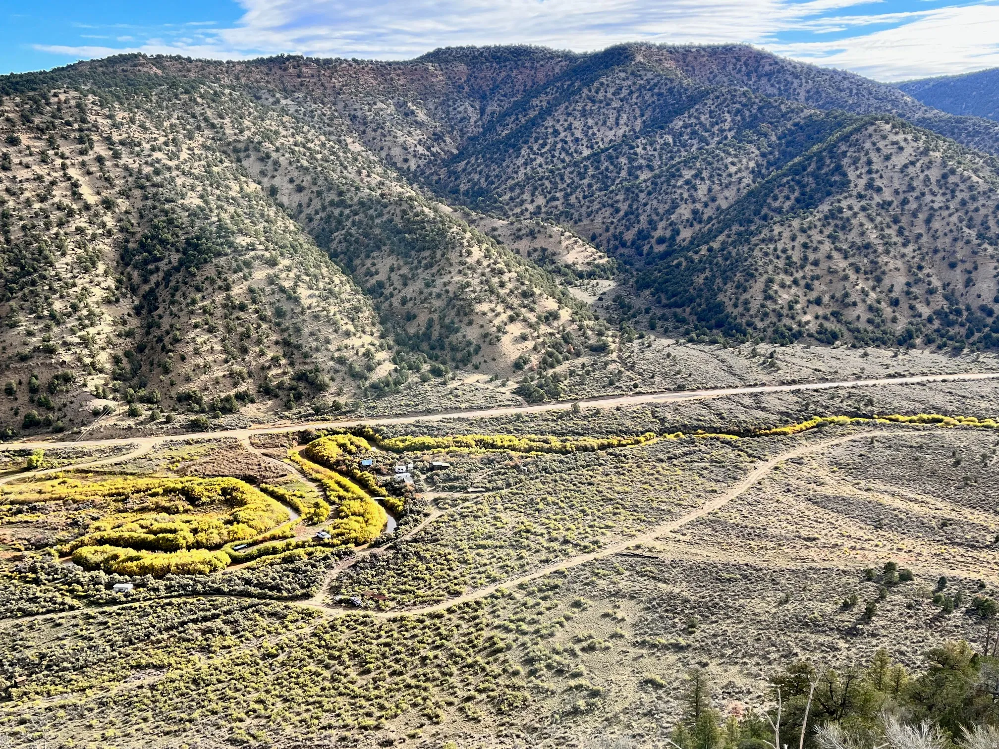 Expansive mountainous terrain with scattered vegetation and a winding dirt road