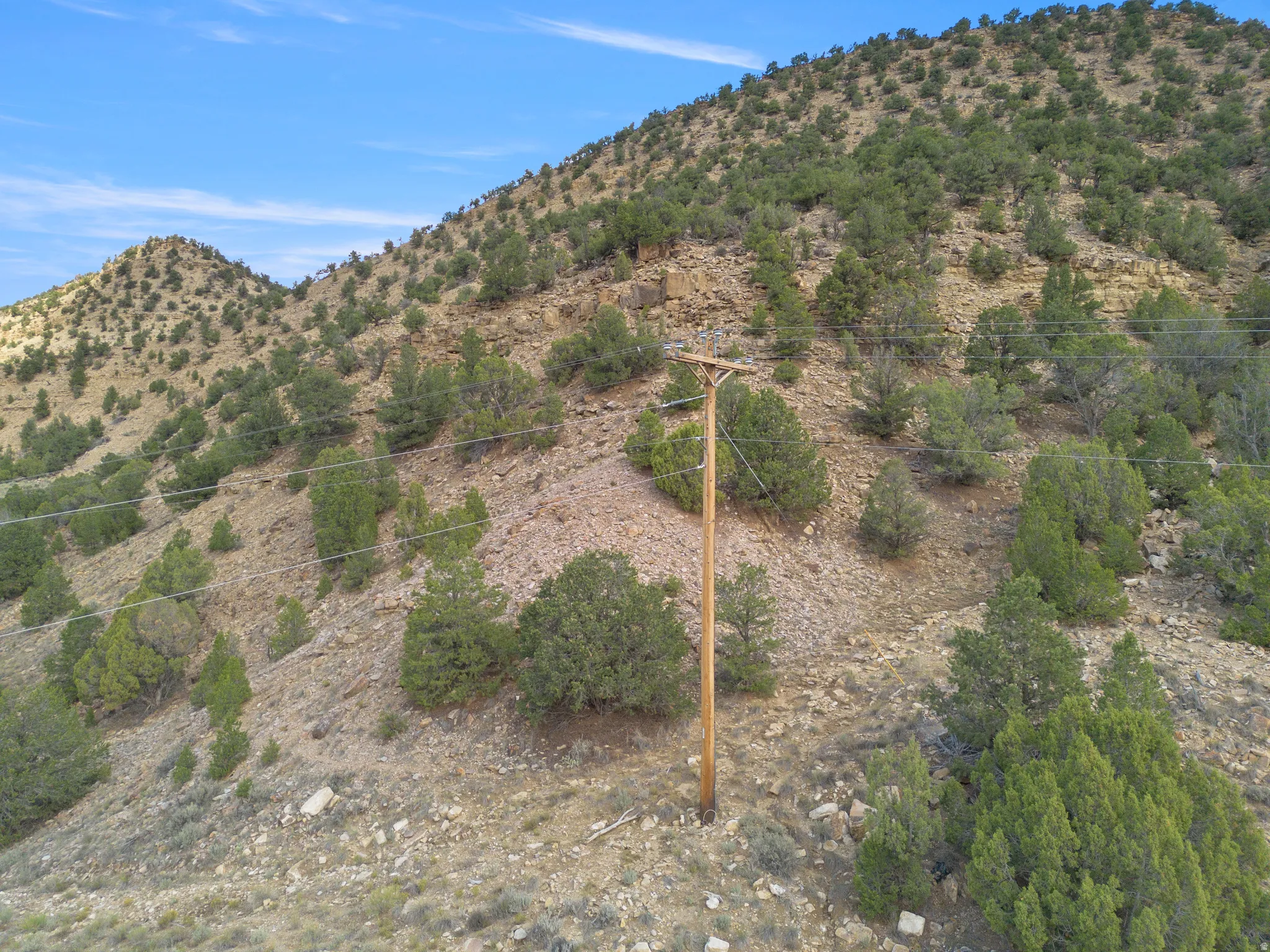 Hilly terrain featuring sparse vegetation and a clear sky