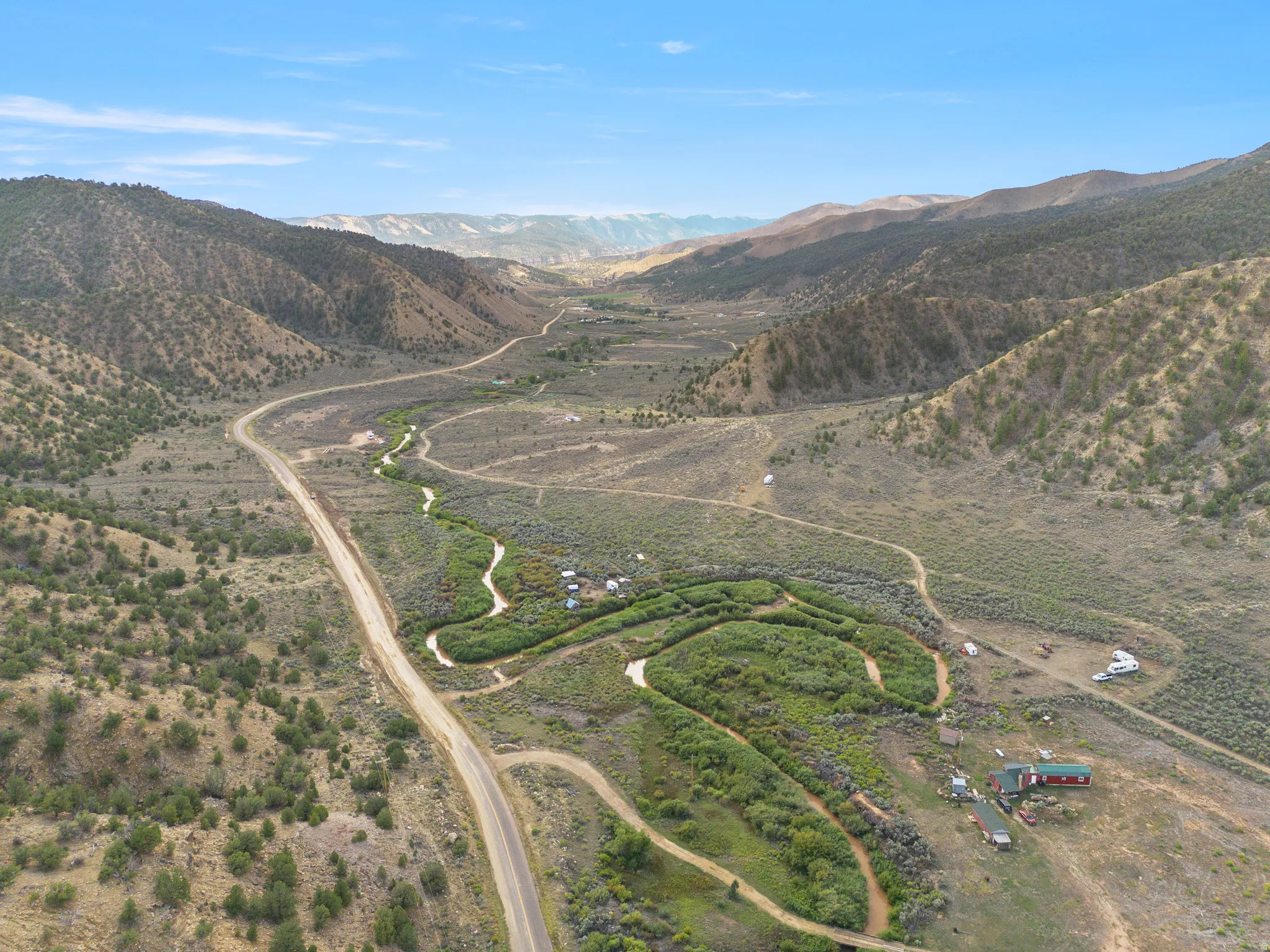 Expansive valley property featuring a winding road, natural waterways, and mountainous terrain