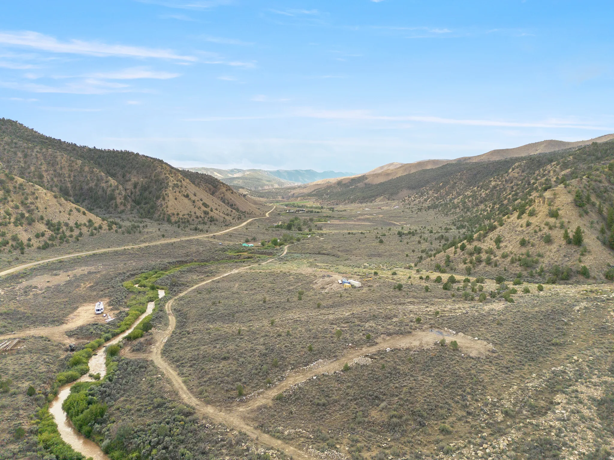 Expansive valley landscape featuring a winding river, distant mountainous terrain, and natural foliage