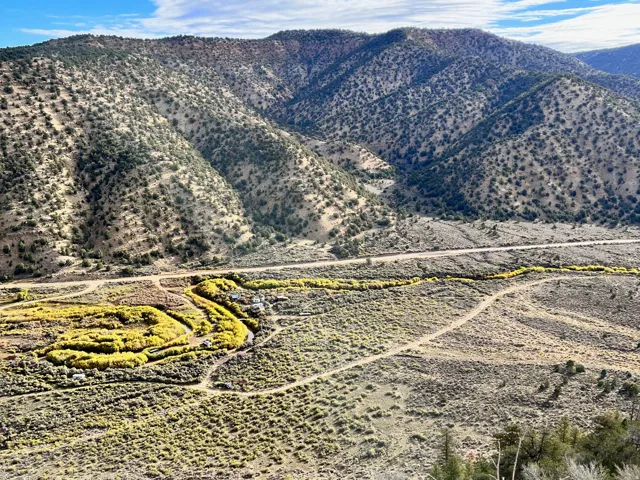 Expansive mountainous terrain with scattered vegetation and a winding dirt road