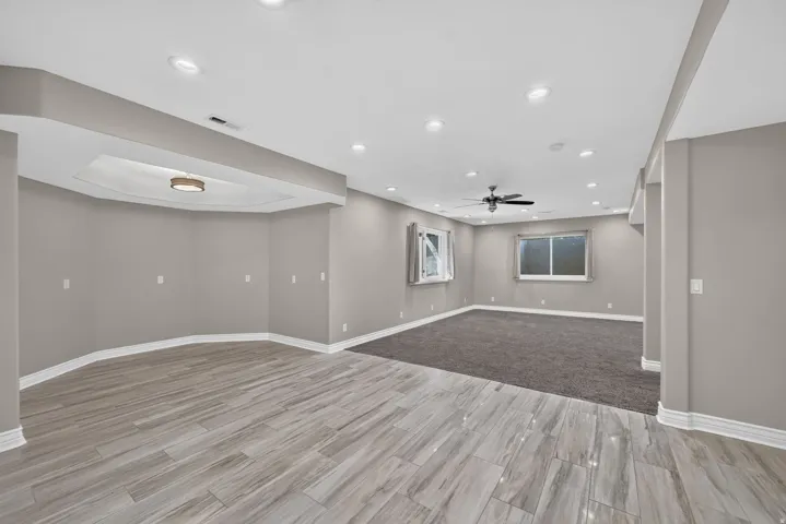 Recessed lighting, ceiling fan, wood-finish flooring, carpeted area, and a tray ceiling with a flush-mount fixture