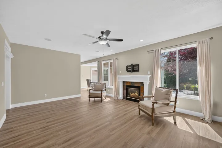 Living area featuring wood-finish flooring, a ceiling fan, recessed lighting, and a fireplace with a mantel