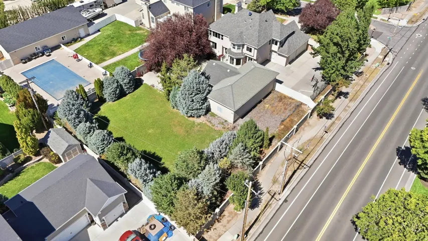 Expansive property featuring a large landscaped lawn, mature trees, a detached auxiliary building, and a paved driveway