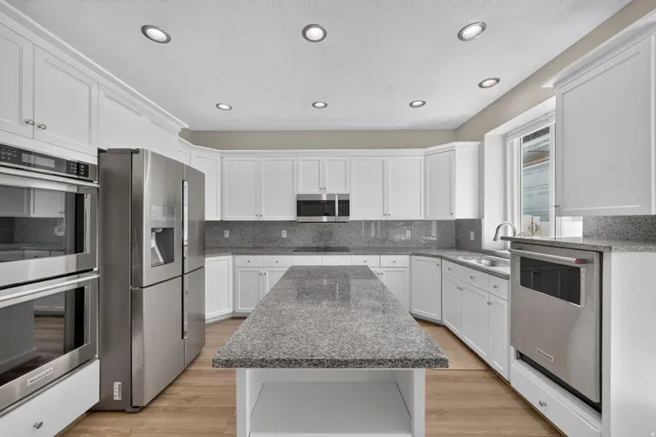 Spacious kitchen featuring white cabinetry, granite countertops, stainless steel appliances, a large center island, and recessed lighting
