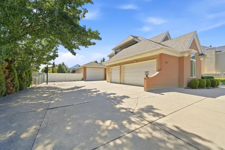 Brick and stucco exterior with multiple garage bays, an arched window, and mature landscaping