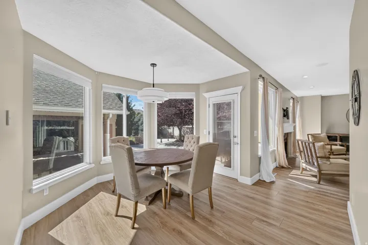 Open-concept living space with wood-finish flooring, a bay window with multiple panes, and a contemporary pendant light fixture