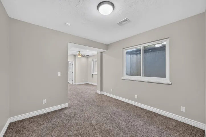 Neutral wall paint, plush carpeting, recessed lighting, and a white-framed window