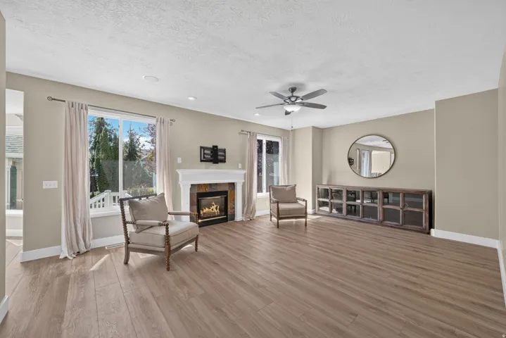 Spacious living area featuring wood-finish flooring, a contemporary ceiling fan, and large windows