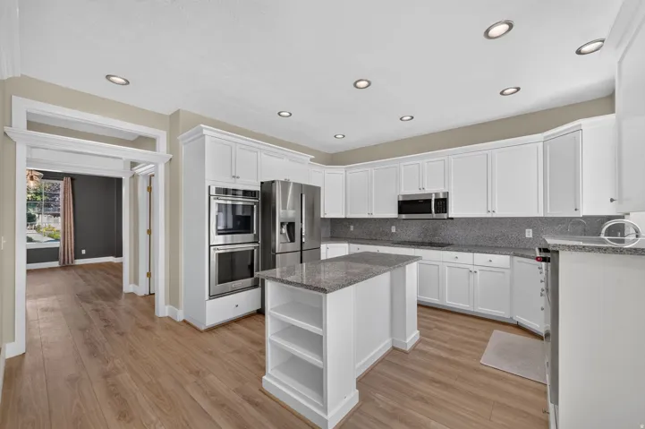 Kitchen featuring white cabinetry, stainless steel appliances, a center island with countertop, recessed lighting, and wood-finish flooring