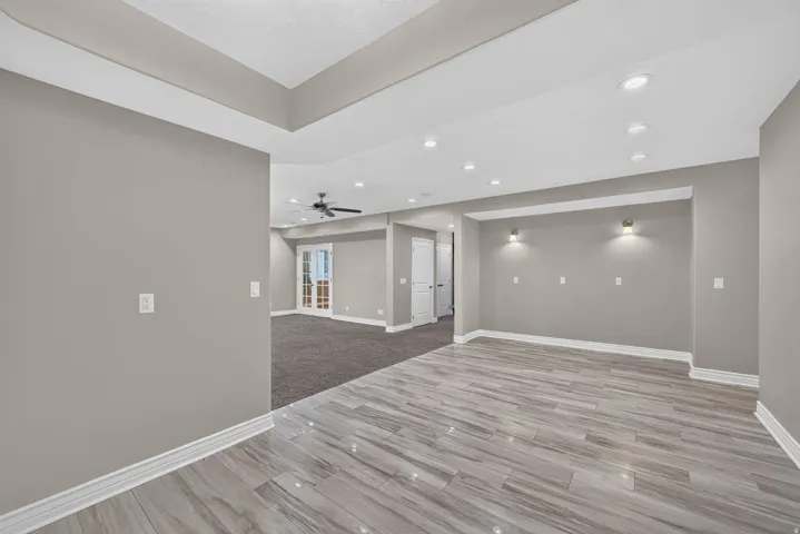 Recessed lighting, tray ceiling, wood-finish flooring, accent wall sconces, ceiling fan