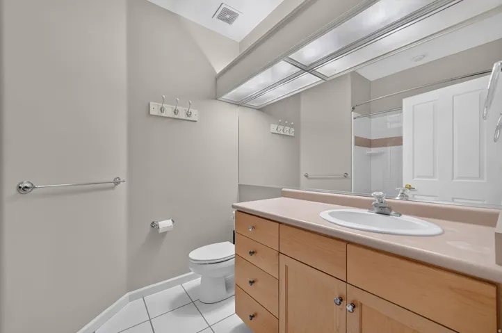 Full vanity with wood-finish cabinetry, integrated sink, and expansive mirror