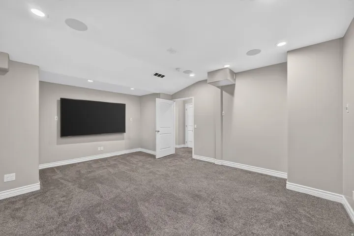 Expansive room featuring recessed lighting, ceiling-mounted speakers, and a large wall-mounted display