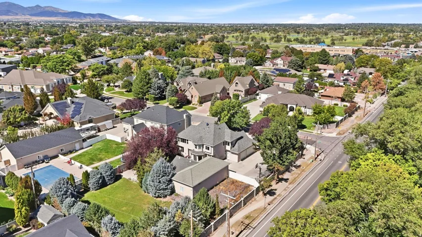 Residential neighborhood featuring established homes, mature trees, and mountainous terrain in the distance