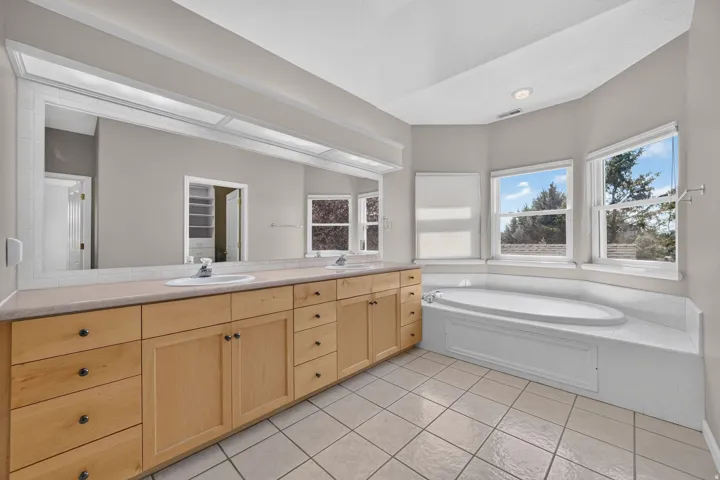 Dual vanity with wood-finish cabinetry, integrated sinks, and a full-width mirror