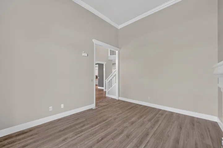 Vaulted ceiling, crown molding, wood-finish flooring, light neutral wall paint, white trim