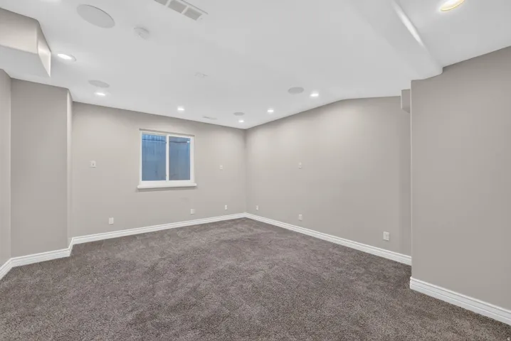 Recessed lighting, wall-to-wall carpeting, and a window for natural illumination