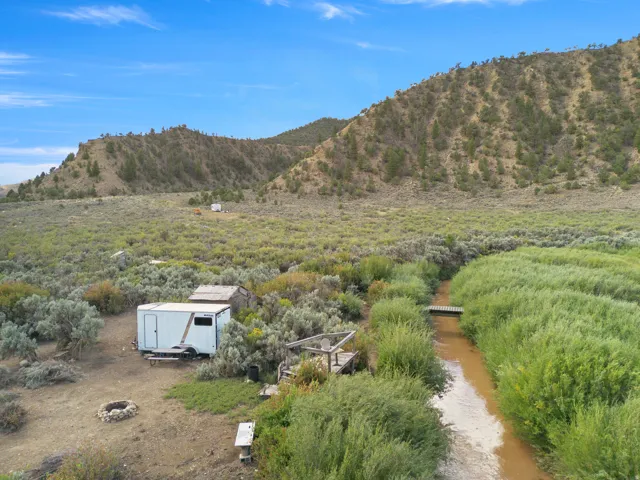 Expansive property featuring a natural water channel, wooden footbridge, and a fire pit