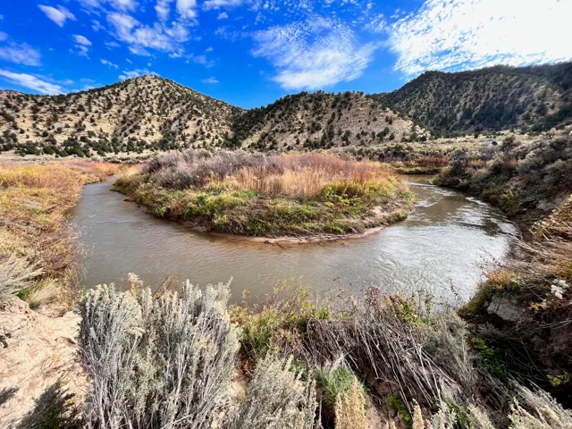 Winding river with natural banks, surrounded by varied native vegetation and distant hills