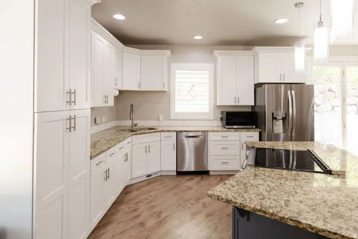 Kitchen featuring white shaker cabinetry, granite countertops, stainless steel appliances, wood-finish flooring, and recessed lighting