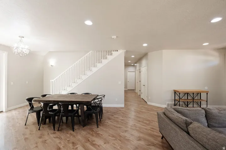 Wood-finish flooring throughout, recessed lighting, and a white staircase with balusters