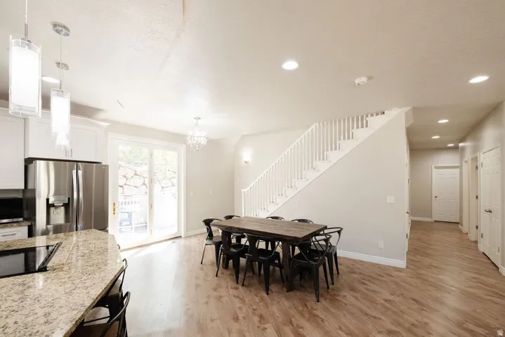 Open concept living space featuring wood-finish flooring, white cabinetry with stone countertops, and recessed lighting