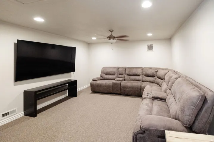 Recessed ceiling lighting, ceiling fan, carpeted flooring, and wall-mounted media console