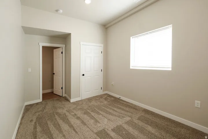 Neutral wall paint, plush carpet flooring, white trim, recessed lighting, and a window with blinds