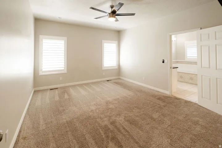 Spacious room featuring neutral carpeting and a ceiling fan