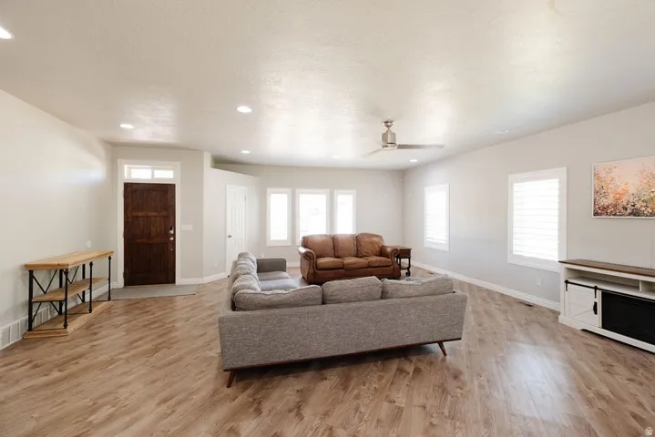 Spacious living area featuring wood-finish flooring, recessed lighting, and a ceiling fan