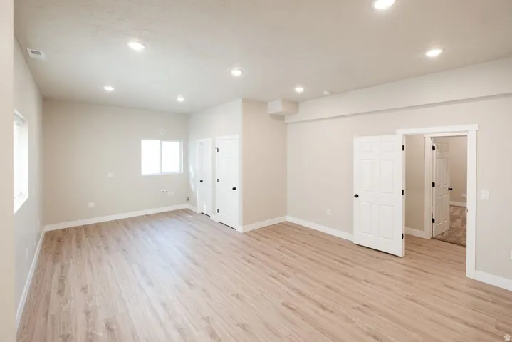 Spacious room featuring wood-finish flooring, recessed lighting, and multiple windows