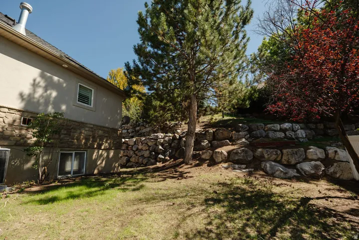Stone-accented exterior with stucco siding and a tiered rock retaining wall