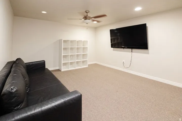 Plush carpet flooring, recessed lighting, ceiling fan, and wall-mounted television