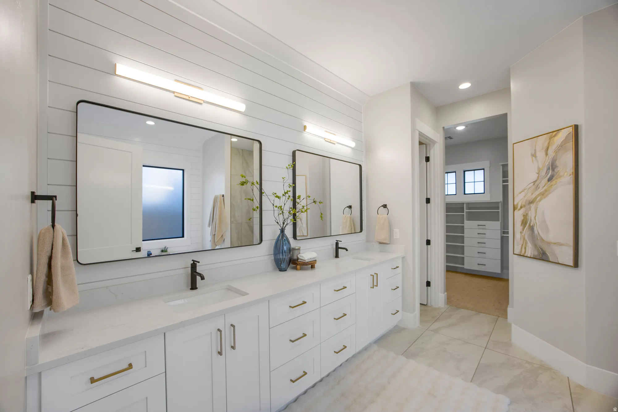 Dual vanity with white cabinetry, gold-finish hardware, and matte black fixtures