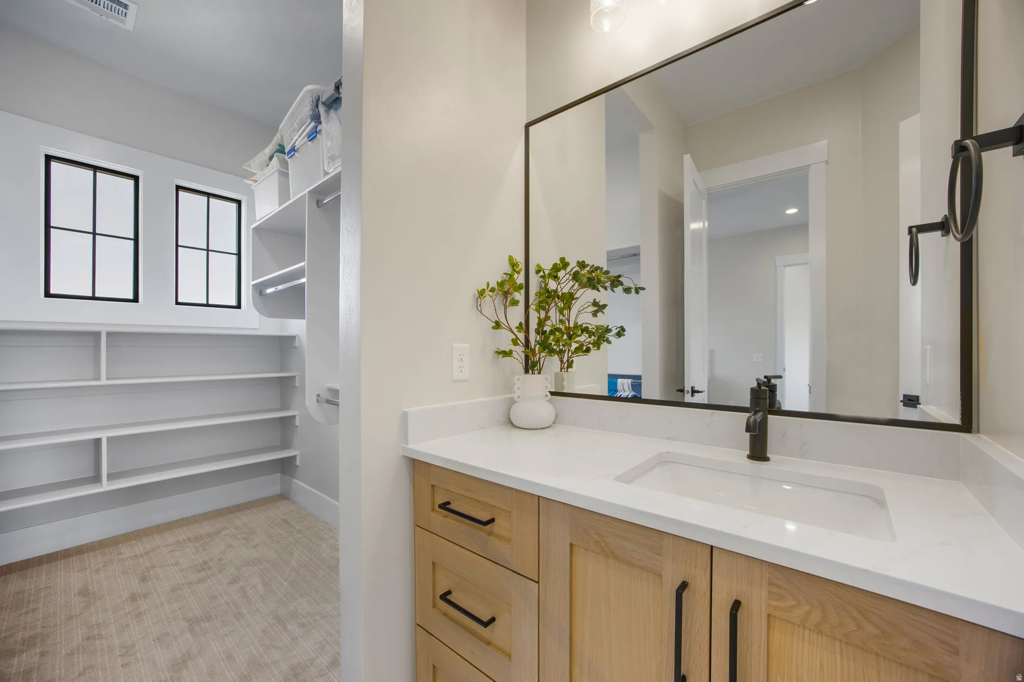 Vanity with a rectangular undermount sink, light wood-finish cabinetry, and a light-colored countertop