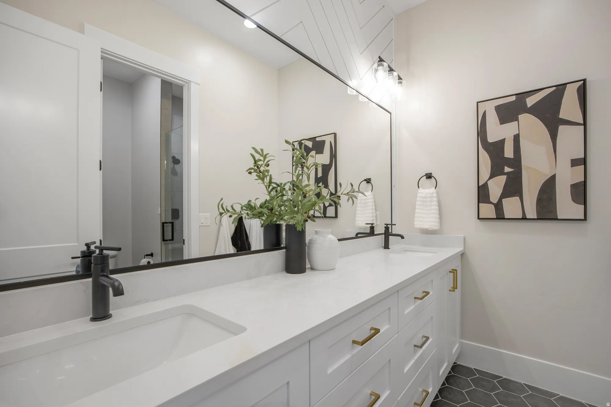 Double vanity with integrated sinks, white countertops, matte black faucets, and hexagonal floor tiling