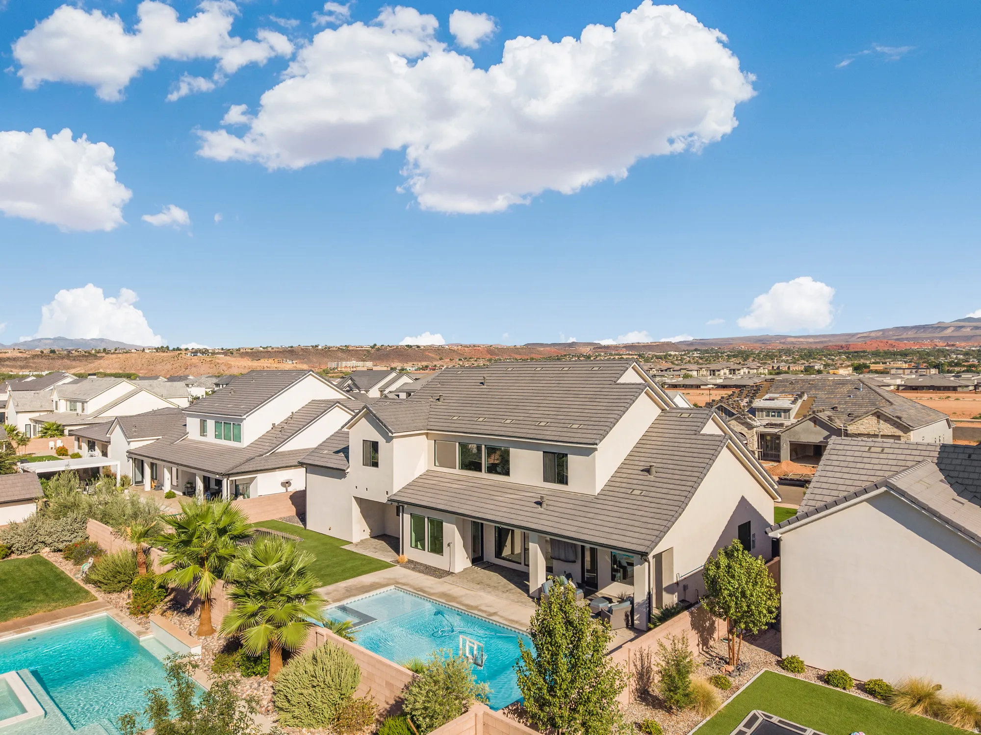 Modern stucco exterior with a tiled roof, featuring a built-in swimming pool and a covered patio