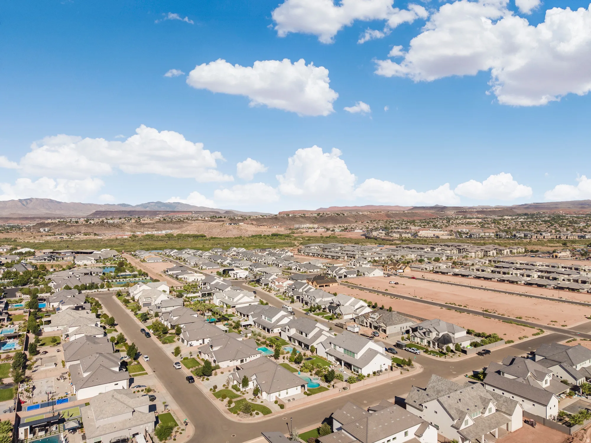 Expansive residential development featuring a structured street layout, uniform rooflines, and distant arid mountains