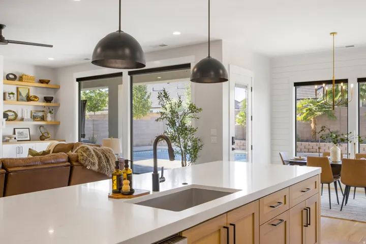 Kitchen island with a built-in sink, light wood-finish cabinetry, and pendant lighting