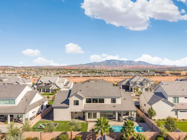 Modern stucco exterior with a tile roof, featuring a built-in swimming pool, a covered patio, and mature palm trees