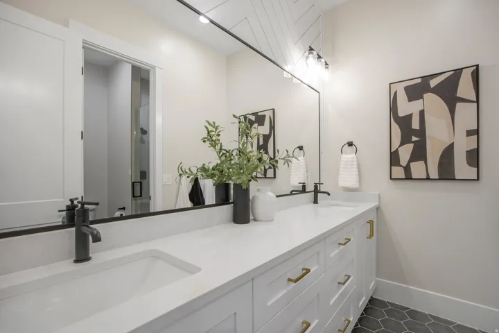 Double vanity with integrated sinks, white countertops, matte black faucets, and hexagonal floor tiling